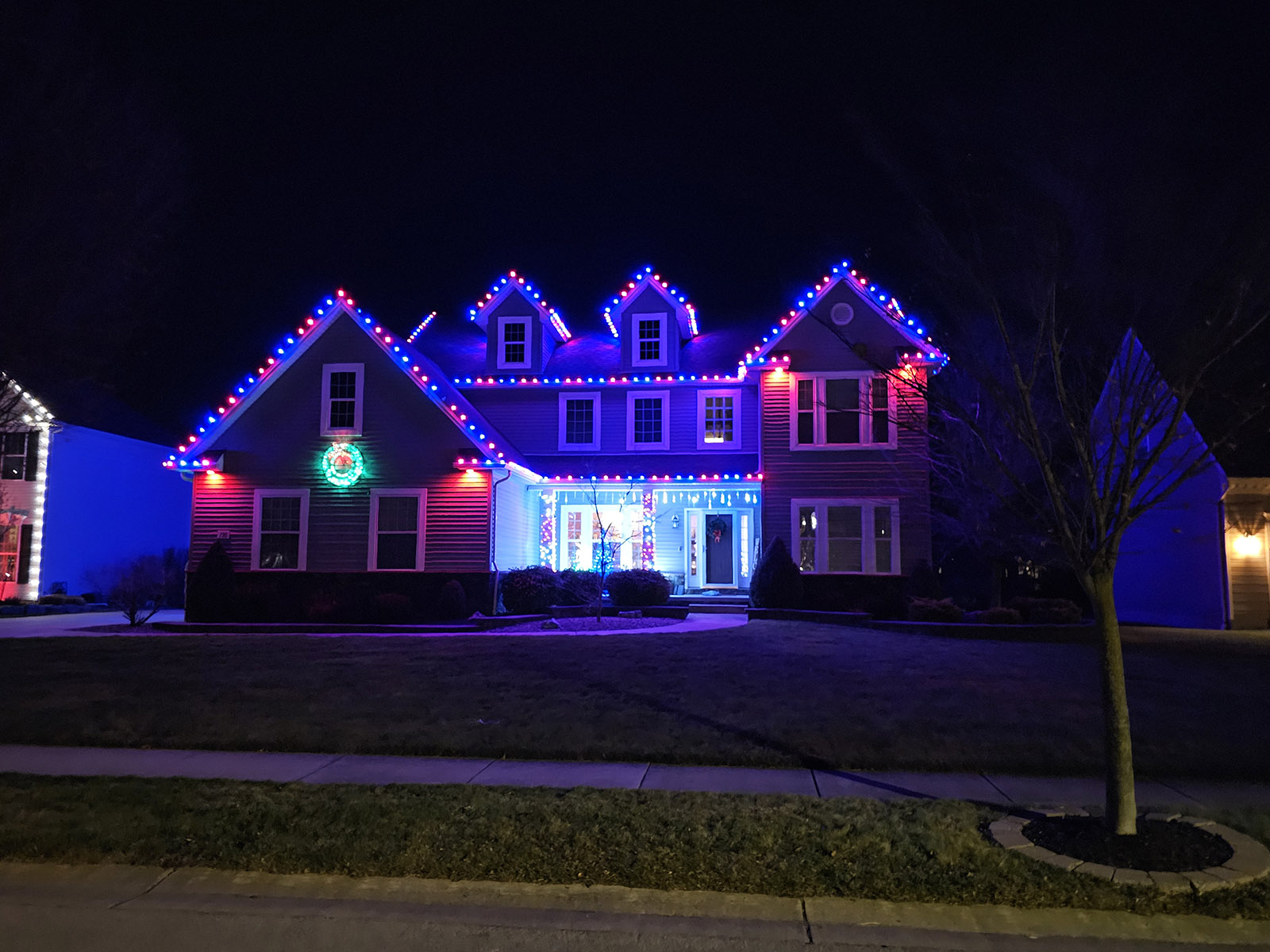 Red and blue holiday lighting on a snowy home by S&K Holiday Lighting